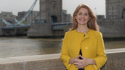 Rachel Bentley, Liberal Democrat Candidate for Bermondsey and Old Southwark, standing by the Thames next to Tower Bridge dressed in a yellow jacket